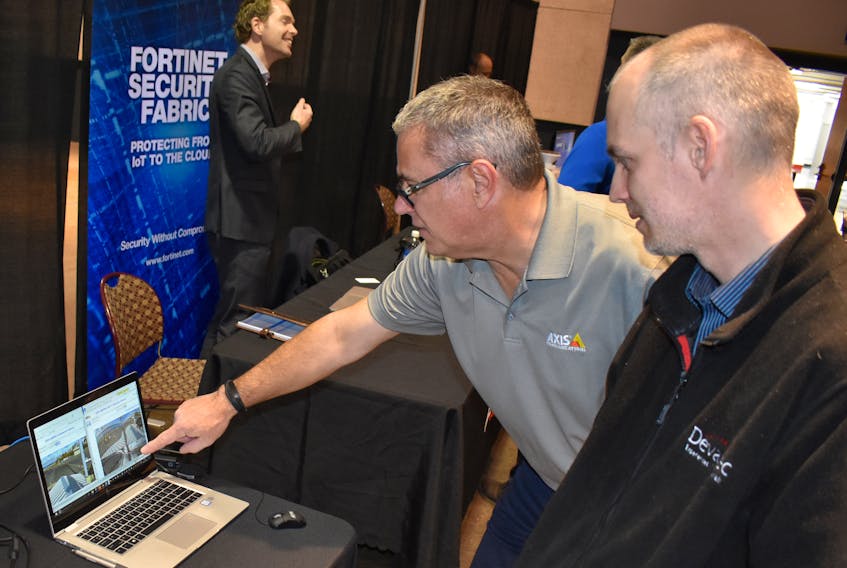 GREG MCNEIL/CAPE BRETON POST - Danny Mimeault, far left, regional sales manager for Axis Communications, demonstrates a company product during the information technology and security showcase in Sydney on Thursday.