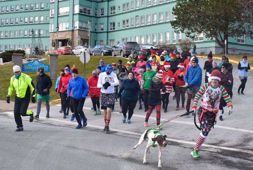 A seasonally themed-clad Yvonne Jessome, front right, leads Reginald the dog and about three dozen human runners from the front of the Northside General Hospital at the start of the sixth annual Boxing Day 5K Run that was held to raise awareness and funds for adolescent addiction and mental health resources. The run was organized by Dr. Stephanie Langley with the assistance of the Northside/Harbourview Hospital Foundation.