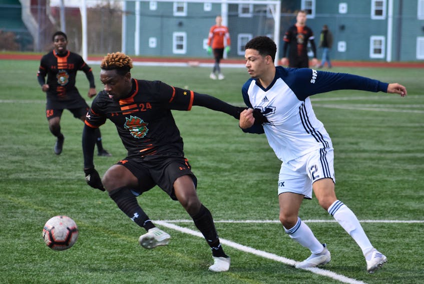 Daniel Williams of the Cape Breton Capers, left, protects the ball as Blake Fenton of the St. Francis Xavier X-Men pressures during Atlantic University Sport men's soccer action at the Cape Breton Health Recreation Complex in Sydney on Friday. Cape Breton won the game 3-1.