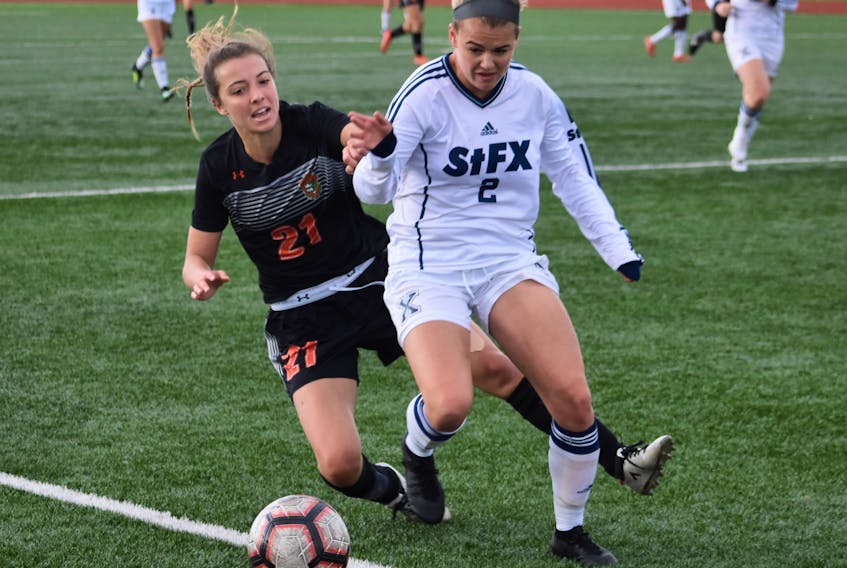 Rachel Leck of the Cape Breton Capers, left, fights for the battle with Megan Frost of the St. Francis Xavier X-Women during Atlantic University Sport action at the Cape Breton Health Recreation Complex in Sydney on Friday. The X-Women won the game 3-2.