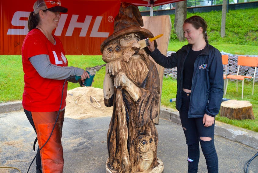 Chainsaw wood carving artist Tracie Dugas, left, puts the finishing touches on her wizard sculpture while daughter Allie helps touch up the just-completed artwork with some oil. Dugas was part of a group of chainsaw artists who created and exhibited their work on the grounds of the Joan Harriss Cruise Pavilion in Sydney on Sunday and Monday as part of the municipality's Canada Day weekend celebrations.