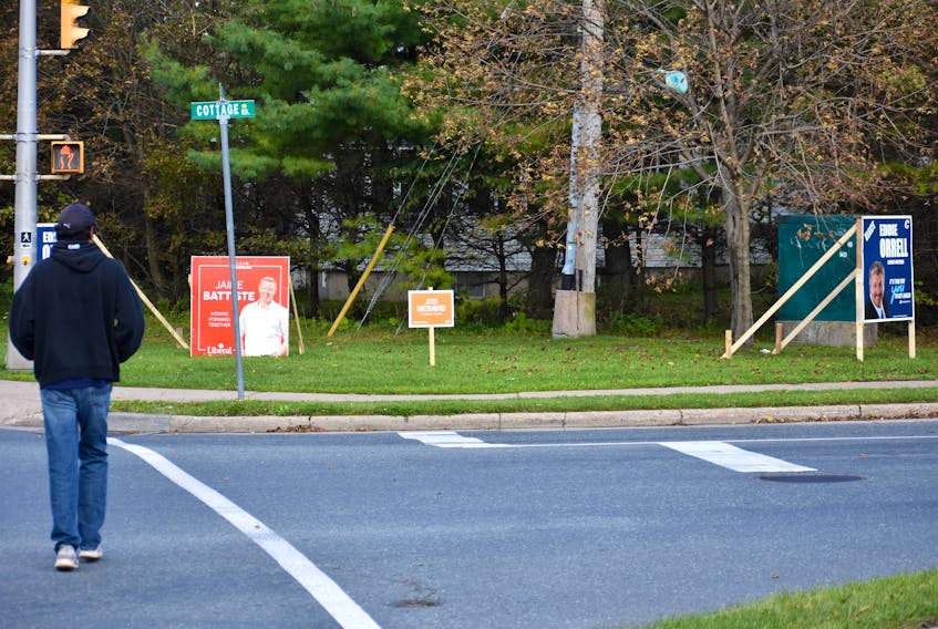 A man crosses the street at the corner of George Street and Cottage Road in Sydney on Monday. The intersection is usually crowded with signs during elections, but only a handful are staked into the grass with less than three weeks to go before the Oct. 21 federal election.
