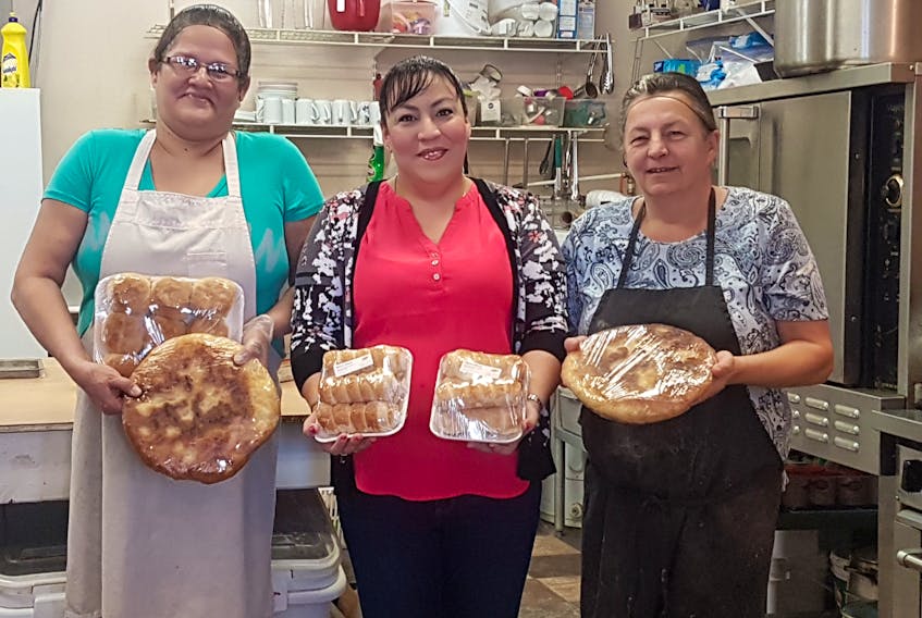 Mona Morris, centre, displays a few of the products that keep people returning to her Eskasoni bakery. Morris holds her famous cream horns while her employees hold biscuits and four cents cake, a type of fried bread. From left to right are employee Julia Young, Morris and Donna Poulette, who taught Morris much of her baking knowledge.