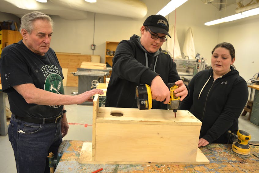Bart Connors, left, a volunteer with the woodworking program at Breton Education Centre in New Waterford, assists Jacob Starzyczny and Katlyn Donahue build duck nesting boxes for a Port Morien Wildlife Association project. The boxes provide a secure place predators for ducks to lay eggs.