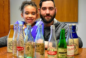 J.R. Reid and his daughter Marley Reid pose with some vintage Cape Breton soda bottles.