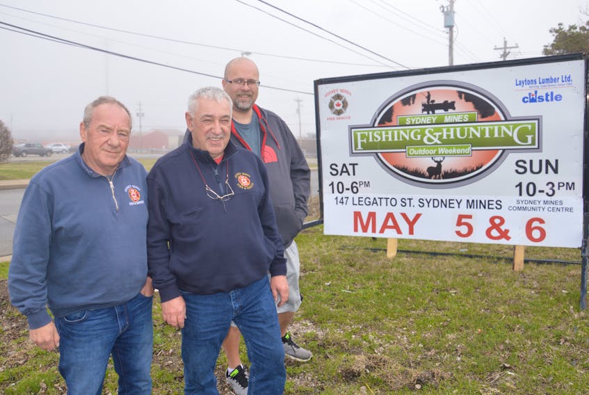 From left, Charles Hawboldt, John MacPherson and Rob Malley stand near a sign on Pitt Street promoting the Sydney Mines Volunteer Fire Department’s annual fishing and hunting outdoor weekend. The show will take place this weekend at the Sydney Mines and District Community Centre and is a fundraiser for the local fire department.