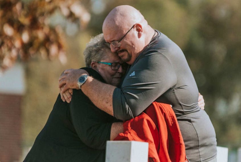 Kerry Balcom gives his sister a hug during an emotional visit to their father’s graveyard in France.