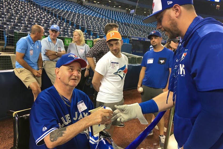 Glen McGean of Sydney chats with Blue Jays first baseman Justin Smoak, far right, his favourite Toronto Blue Jays player, while Smoak autographs a baseball for him, prior to the start of a Major League Baseball game in Toronto Tuesday.