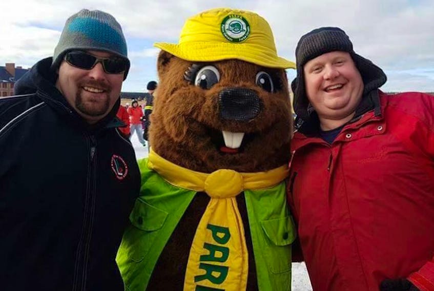Justin Mahon, left, and Brett Hanham enjoy a laugh with the Parks Canada mascot. The two men are members of the George D. Lewis Gateways to Opportunity community economic development organization in Louisbourg. They are planning to hike the closed road that links Gabarus and Louisbourg on Saturday and hope it will get the attention of government officials and remind people that reopening the road is a worthwhile investment.