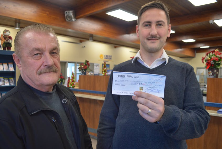 Yianni Harbis, right, manager, branch and commercial banking for the Sydney Credit Union on Townsend Street, stands with Greg MacPhee, a Cape Breton Regional Municipality building inspector, while holding a check the credit union made out for a Cape Breton Firefighters Burn Care Society fundraiser hosted by Cape Breton Regional Municipality building inspectors 11 years ago. MacPhee found the obviously misplaced check last week and says he’s grateful the credit union honoured it after all this time.