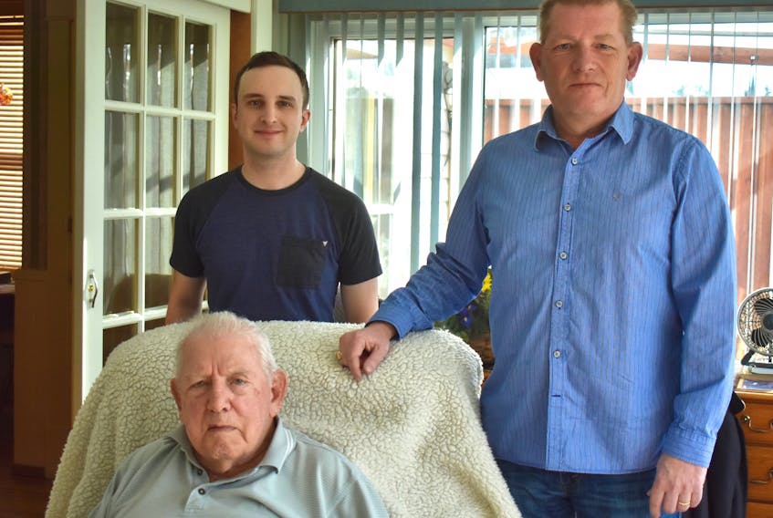 Murray Ryan, who turned 100 on Feb. 1, is shown seated while his grandson Andrew, back left, and son Murray, back right, visit the retired judge at his North Sydney home.