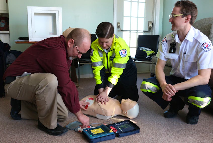 From left, Shawn Luker, director of the Cape Breton Housing Authority, demonstrates the use of an AED (automated external defibrillator) along with Krista Lane, Emergency Health Services community relations paramedic, and Michael Janczyszyn, EHS AED registry co-ordinator, last week at the Donkin Seniors Complex.