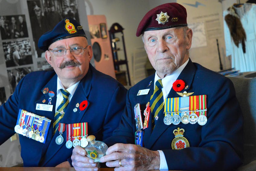 Branch 19 legion members Harry Taylor, left, and Cecil MacLeod pose with a small bottle of sand from the shores of Normandy. The vial was donated by Jackie Green whose father was among the Canadians who landed on Juno beach on June 6, 1944.