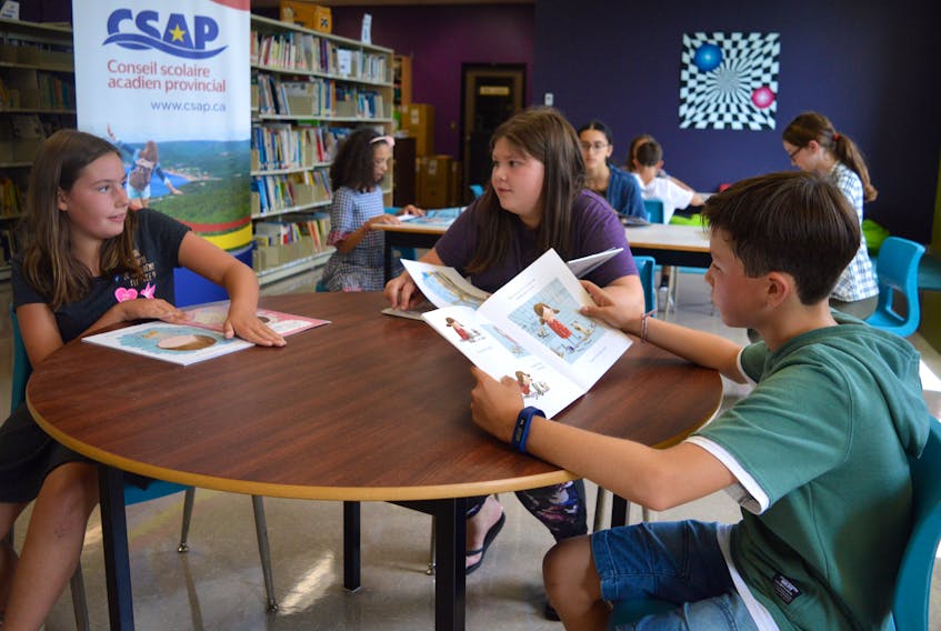 Zoé Poupart, from left, Ciara MacDonald and Jeremy Moneau, students at Étoile de l’Acadie in Sydney, hit the books in the school library Wednesday, on their first day of school. The Conseil scolaire acadien provincial schools headed back to class Wednesday, while students in the English language public school system return Thursday.
