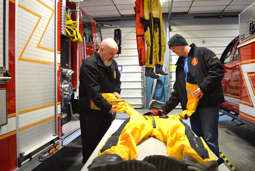 Rickey Jury, left, and Kirk MacNeil, members of the New Victoria Volunteer Fire Department ice rescue team, clean up gear following an unsuccessful rescue attempt. Team members ventured out on thin ice Saturday night in hopes of rescuing Debbie Lee Pearson of New Victoria, whose body was found by police divers on Monday.