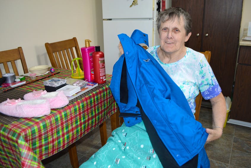 Judy James of Sydney shows some of the many Christmas gifts she received from strangers this year, including a coat she loves so much she said, “I can’t believe it’s mine.” James said the kindness of others changed Christmas for her this year.