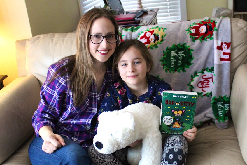 Andrea Donato sits at home with her eight-year-old daughter Sophia, who is holding the stuffed animal and books given to her by staff at the Indigospirit store in Sydney after she lost them at the Mayflower Mall.