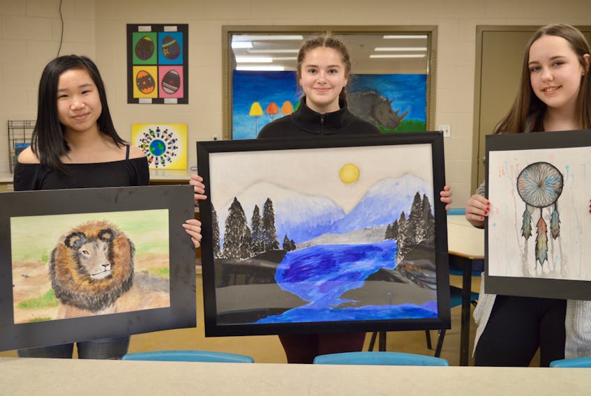 Shown with their artworks are Whitney Pier Middle School Grade 8 students Michelle McIsaac, from left, Katie Clemens and Kayla Baldwin. The students and art teacher Krista Starzomski are getting ready for a student art show that will take place at the Mayflower Mall from Tuesday until April 30.