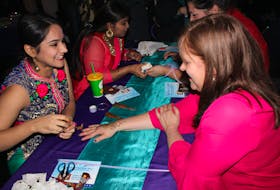 From left, Ekam Dhingra of Punjab, India, a student at Cape Breton University, gives Cathy Horechuk of Westmount a henna tattoo on Wednesday at the Canada Games Complex.