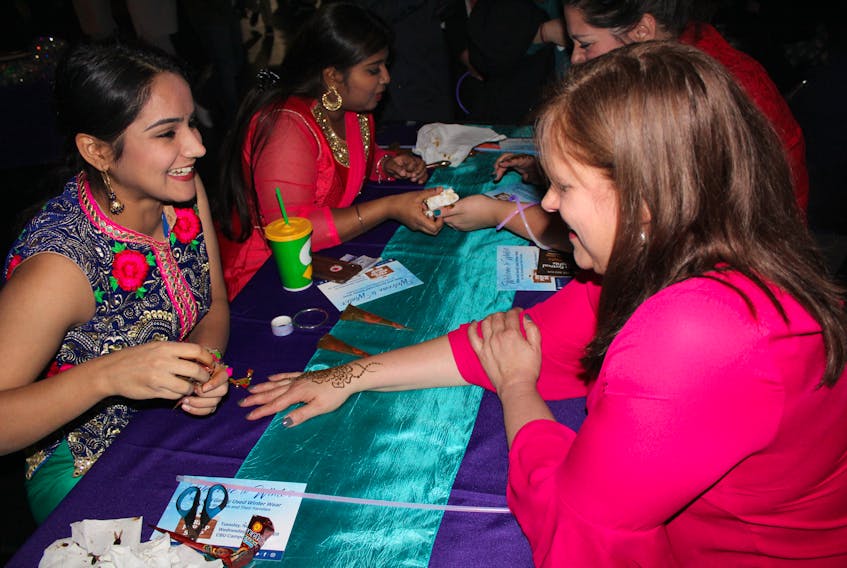 From left, Ekam Dhingra of Punjab, India, a student at Cape Breton University, gives Cathy Horechuk of Westmount a henna tattoo on Wednesday at the Canada Games Complex.