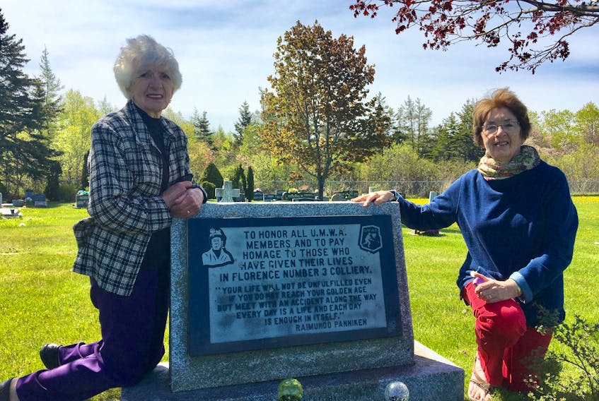Evelyn MacDougall, left, and Eileen Romeo kneel beside a monument that honours miners who lost their lives and those who worked in No. 3 Colliery in Florence. The sisters have been arranging a Miners Memorial Day cemetery service each year since 1999 to honour all miners from their surrounding community.