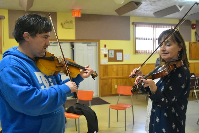 Fiddler Dwayne Cote, left, gives Joan Roach of Glace Bay a few pointers on hand position during Cote’s “Fiddle From Scratch” sessions being held at the Brooks Haven Seniors Recreation Centre in Prime Brook this week, as part of Celtic Colours International Festival.