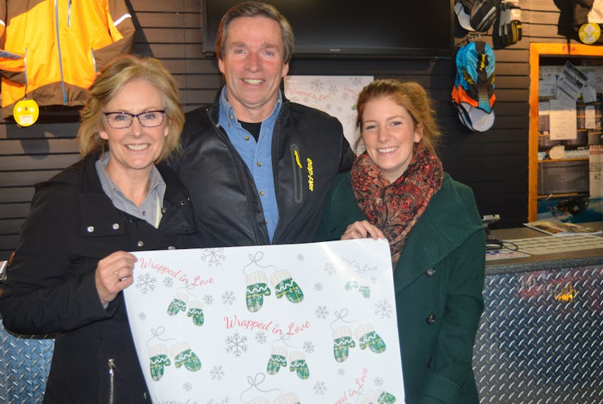 From left to right, Mary MacDonald, Gord MacDonald and Danielle Johnston stand with wrapping paper printed by City Print + for the Wrapped in love fundraiser. The fundraiser donated 10,000 sheets of wrapping paper with 100 per cent of the sales to help purchase winter apparel for children in Cape Breton.