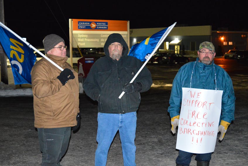 From left, protestors Ray Hooper of Sydney, Ken Wilkie of Leitches Creek and Mark Muldoon of Whitney Pier protest in support of postal workers outside of Canada Post’s mail processing plant on Upper Prince Street in Sydney on Monday night. Hooper and Wilkie are members of the Nova Scotia Government & General Employees Union (NSGEU) and Muldoon is president of the Cape Breton District Labour Council.