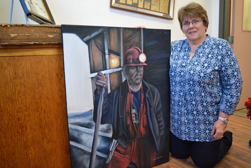 Artist Kim Brown MacDonald of Glace Bay shows an oil painting of coal miner Sandy White, which will be one of 24 pieces of her work featured in a solo show at the Main Street Art Gallery in the New Waterford Credit Union. The show opens Friday from 3-5 p.m.
