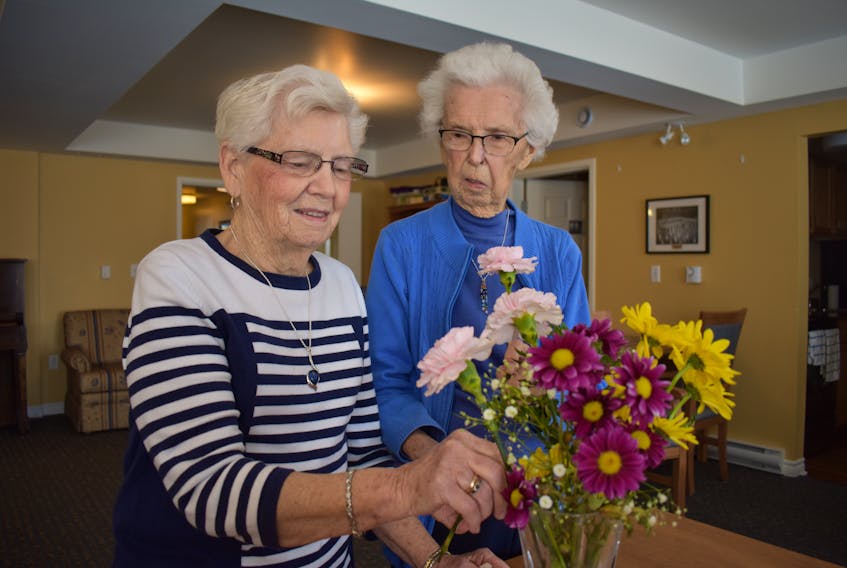 Mamie Johnstone, left, and Yvonne Johnstone look at a flower bouquet on Tuesday. The sisters-in-law are the longest serving members of the North Sydney Garden Club, which will kick off its 60th anniversary with an open house on Saturday at the Cape Breton County Exhibition on Regent Street in North Sydney.