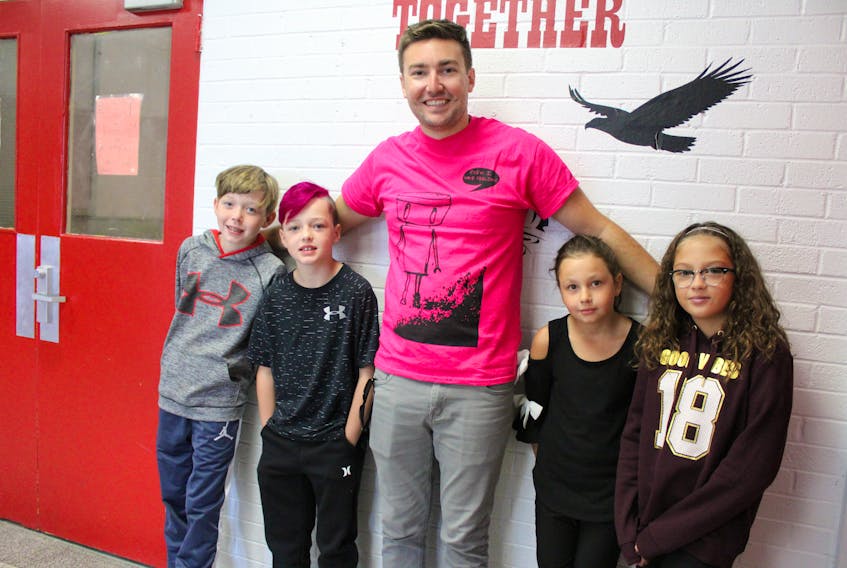 Travis Price, centre, stands with some Grade 5 students after his presentation at Tompkins Elementary School on Tuesday. The students are, from left to right, Hayden Graham, 10, Caleb Green, 10, Madison Stanley, 10, and Taryn Boone, 10.