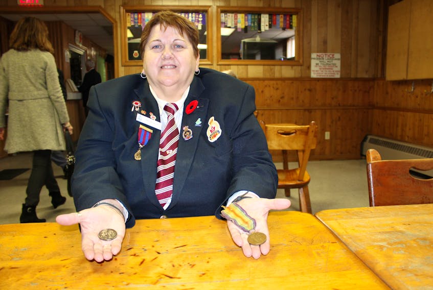 Ann Mischiek, a member of the ladies auxiliary of the Royal Canadian Legion branch 12 in Sydney, holds two medals from the First World War in her hands while sitting at the legion on Sunday. The medal on the left is the King George medal, which was in the pouch with her great-uncle’s medals. It belonged to P. Campbell and Mischiek is hoping to track down Campbell’s family members to give it to them. The medal on the right is the Victory Medal, which was awarded to her great-uncle John Alex Shaw.