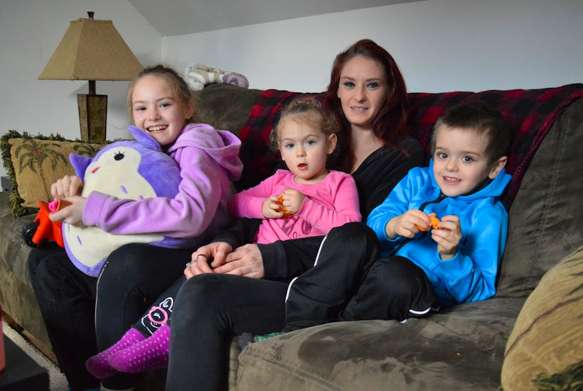 From left, nine-year-old Leah Ligaj, two-year-old Isabelle MacLeod and five-year-old Caydon MacLeod sit with their mother, Tracey Ligaj, on the sofa of a friend’s home on Tuesday. The 27-year-old single mother is staying there after a fire on Feb. 10 forced them out of the duplex they were renting. Ligaj said she is thankful she woke up that night and was able to get her family to safety.