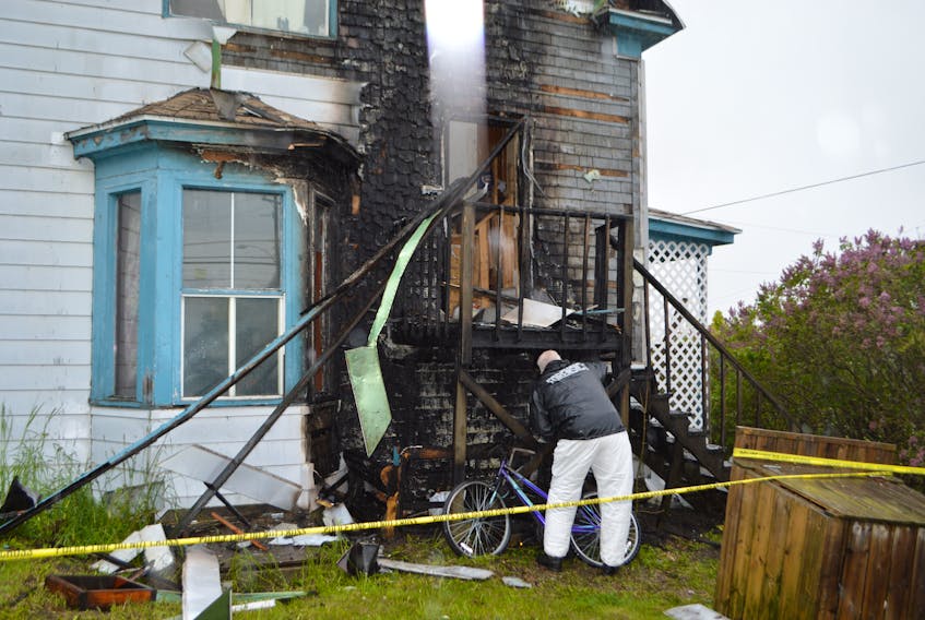 Sgt. Geoff MacLeod of the Cape Breton Regional Police Service's forensic identification unit looks through debris around the steps at a two-unit apartment complex at 592 Upper Prince St. in Sydney on Wednesday, assisting the fire marshal's office in investigating the cause of a fire that broke out at about 9:30 p.m. Tuesday night. The fire has displaced five people.