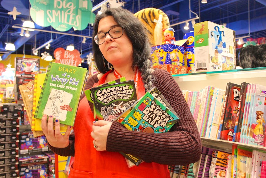 Crystal Alexander, a worker at Mastermind Toys in Sydney, holds some books from the popular “Diary of a Wimpy Kid” and “Captain Underpants” series. Michelle AuCoin, the executive director of LearnAbility Cape Breton, says literacy skills are declining sharply and books make ideal Christmas gifts for children. “When parents come to us and they ask for suggestions, we love to give them suggestions for books.”