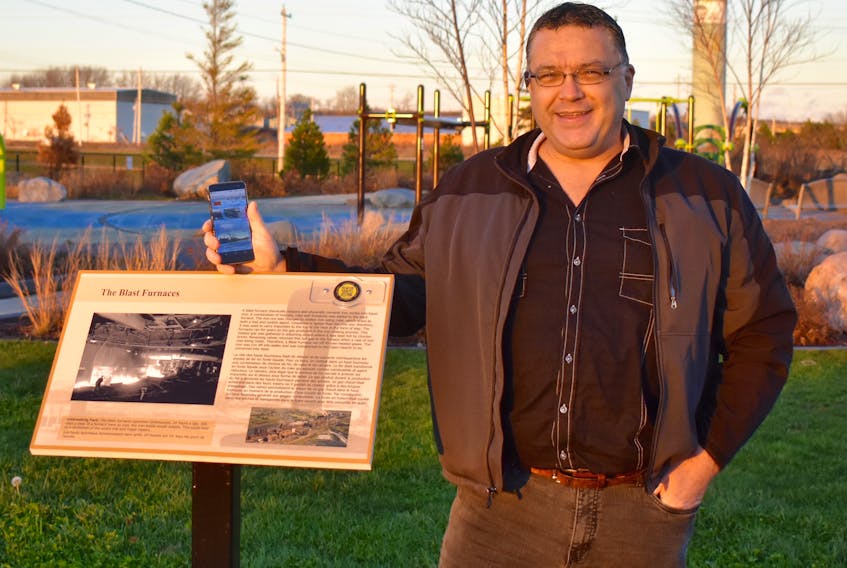 Communications engineer Ron Campbell stands beside one of Open Hearth Park’s interpretive panels that display stories about the former Sydney steel plant that once stood on the site. Campbell and his IT company Tapnbe Inc. have affixed ‘yellow tags’ on the signs that link smartphones and devices to online video content about the industrial complex and its place in Cape Breton history.
