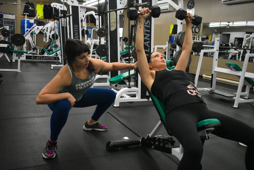 Vicky McNeil of New Waterford, left, watches client Jennifer Budden-White’s form during a set of inclined chest press exercises. Before doing personal training sessions with McNeil, who owns Mindful Motion Fitness, Budden-White said she didn’t do arm exercises because she was frequently injuring herself.