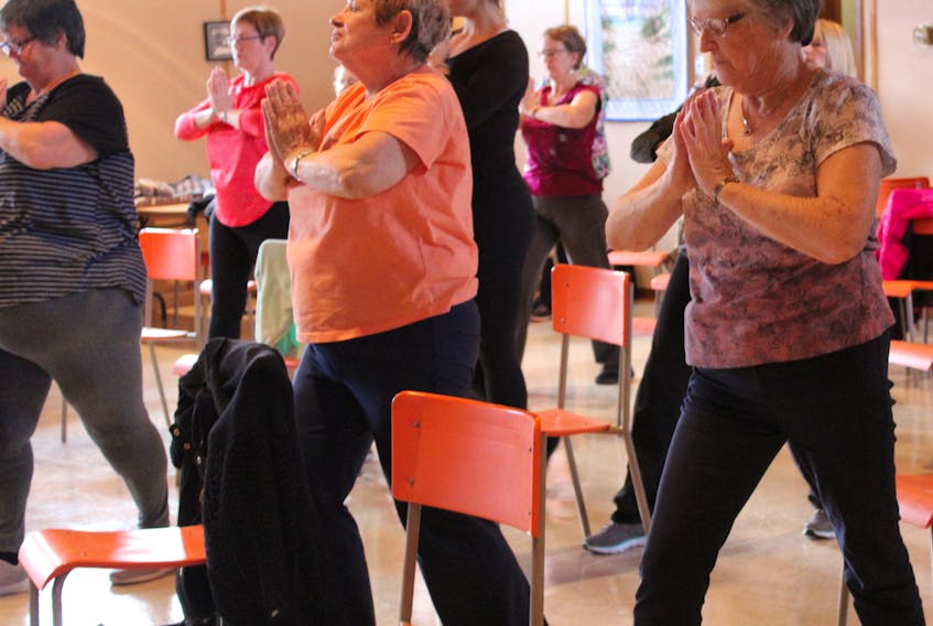 Isabelle Morrison, right, practices a variation of prayer pose during chair yoga class at Warden United Church on Nov. 12. Morrison started organizing the chair yoga classes in Sept. 2017.