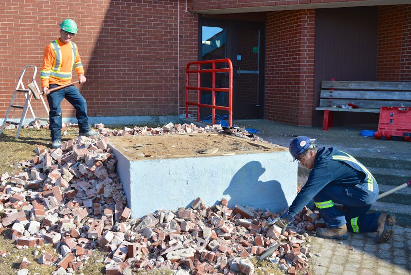 Paul MacInnis, left, and Jamie McPhee, labourers with Joneljim Concrete Construction, remove bricks from the tower that held plaques at the Cape Breton Miners’ Museum in Glace Bay. The second phase of the repairs to the museum began Thursday.