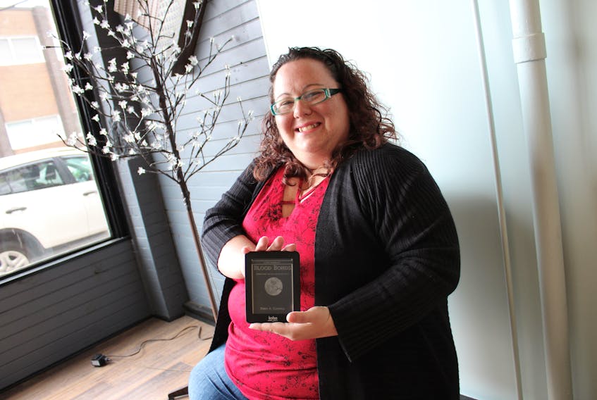 Kerry A. Campbell holds an e-reader featuring her new book “Blood Bonds: Stories from the Lily and Quinn Series” which was released through online stores Oct. 1.
