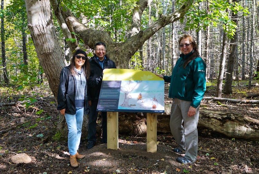 Mary Louise Bernard, right, author of "Sweetwater Maiden: The Mi'kmaw Legend of Maple Syrup" and a Parks Canada interpreter, stands with artist and illustrator Dozay Christmas, and her husband Senator Dan Christmas, near one of five interpretive panels recently installed at MacIntosh Brook in the Cape Breton Highlands National Park. These panels tell the story of a young Mi’kmaw maiden who first discovers sismoqnapui/maple sap. JEFF BEAR PHOTO