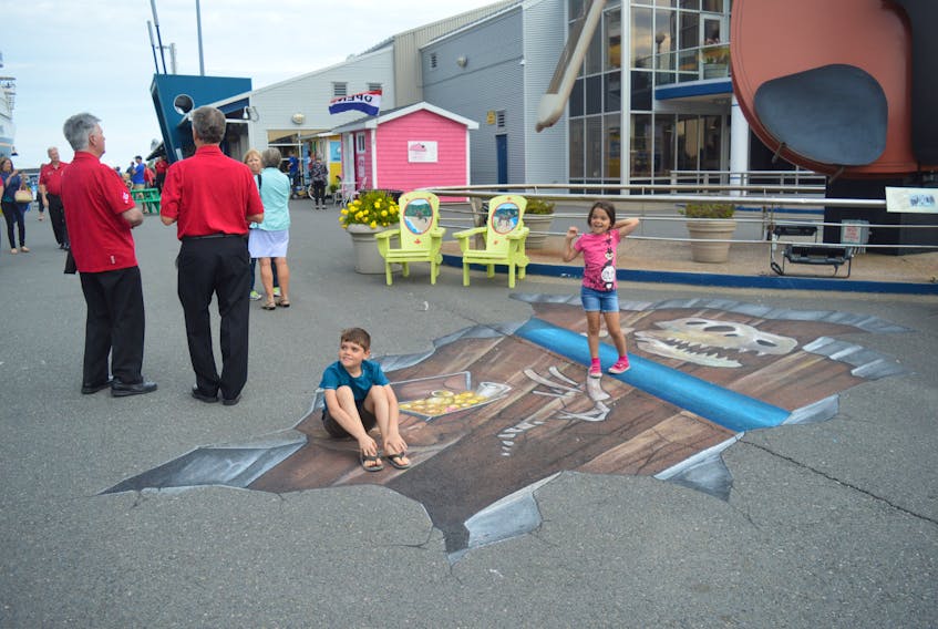 Isaac Babin, 8, sits on the ledge in the 3D chalk painting done by Dave Johnston, while his sister, Magali Babin, 6, stands on the ledge.
