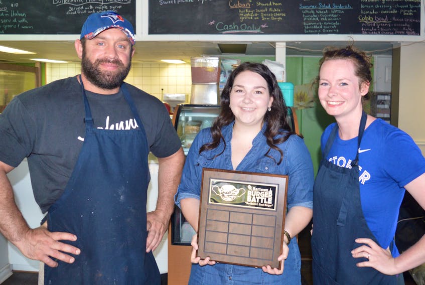 In this file photo, Genegieve Andrea, centre, presents James Donato and Amanda Sheffield, co-owners of Commercial Street Deli in North Sydney, with a plaque for winning the Bartown Burger Battle last July. The Bartown Burger Battle has returned for its second year and is currently underway on the Northside.