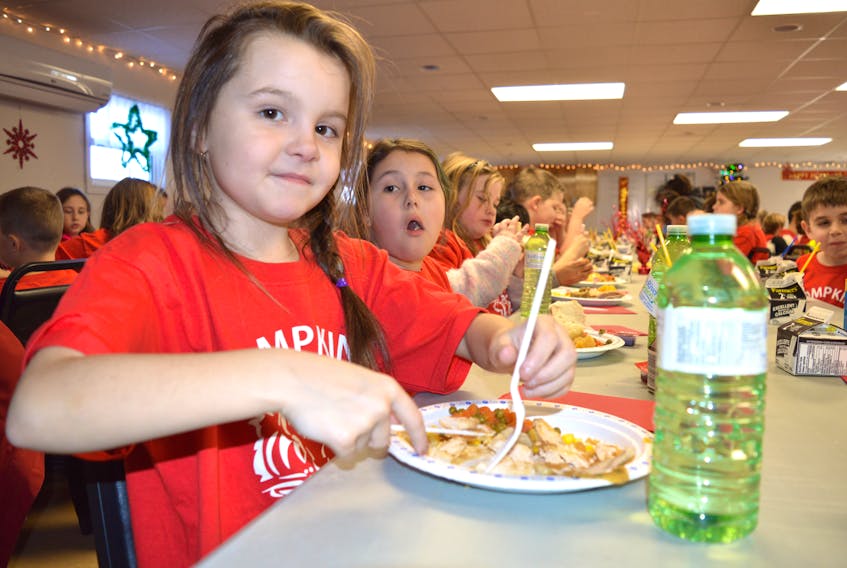 Keely Robins of Reserve Mines, a Grade 3 student at Tompkins Memorial Elementary School, eats a Christmas dinner at the Reserve Mines Seniors and Pensioners Club recently. The school partnered with community organizations and businesses to host the dinner for the 230 students as well as staff and community partners.