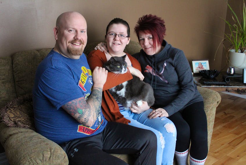 Alyssa Rose, centre, holds her cat Wally while sitting in the living room of their family home with her father Shawn Rose and mother Lynn Rose. The 13-year-old Malcolm Munroe student was told on Wednesday the tumour on her brain stem that was surgically removed in October was filling in and she needed radiation to try to stop its growth.