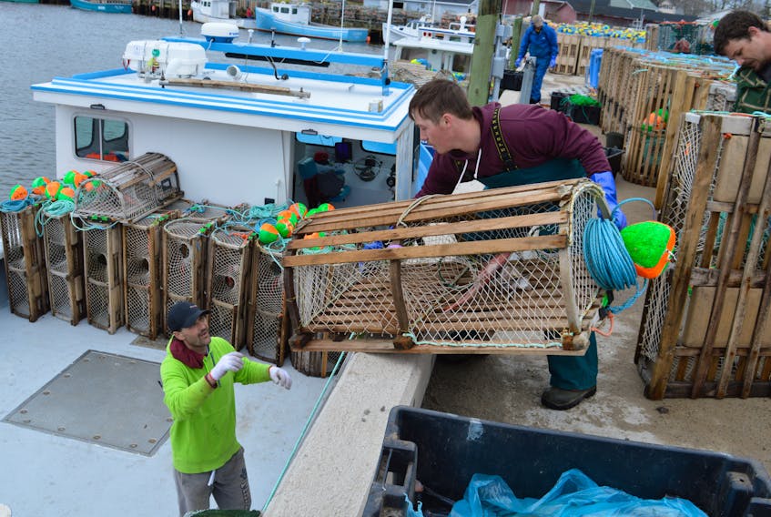 From the left, Kevin Ogley, receives a trap from Dylon Turnbull and Kevin Ogley on board the Mark and Brett. The season continues until July 15 in lobster fishing area 27.