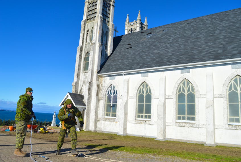 Master Cpl. Mike Dingman, left, and Master Cpl. Michael Galbiati-Bourassa collect cable outside the former St. Alphonsus church on Tuesday.