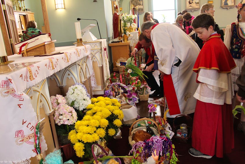 Thirteen-year-old altar boy James Clarke looks down at the Easter baskets that were blessed Saturday at St. Mary’s Polish Parish. As part of the annual tradition in Whitney Pier, greeters hand out flowers to all who enter the church as a sign of friendship.