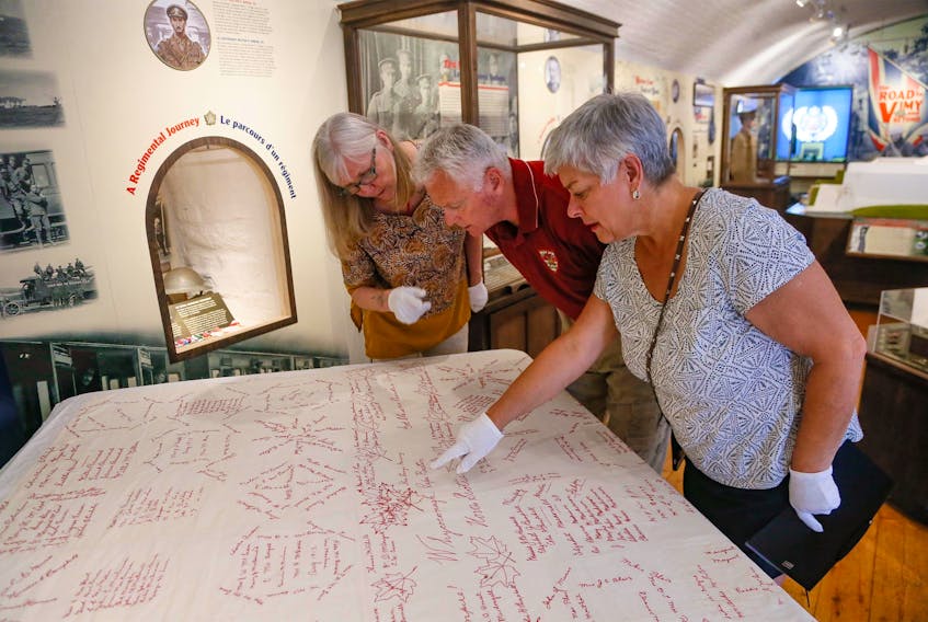 Carla Jensen, Ken Hynes, chief curator of the Citadel Army Museum, and Leslie Hobson, examine a war quilt Jensen and Hobson brought back to its town of origin, Whycocomagh. They are seen at the museum in Halifax on July 20.