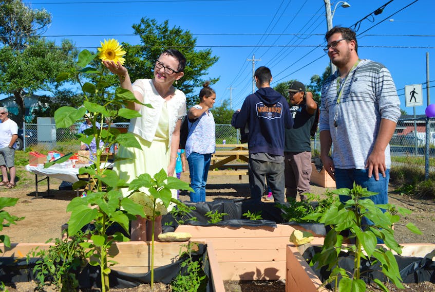 Brandon Jolie, 22, garden co-ordinator of the New Aberdeen Revitalization and Affordable Housing Society, shows Eileen Flynn around the community garden dedicated to her late husband Darrell Flynn, during a ceremony in Glace Bay on Friday.